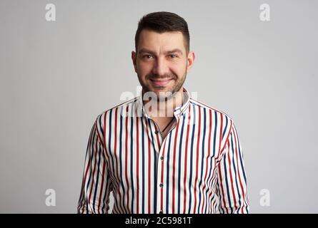 Der gutaussehende bärtige Mann lächelt. Studioaufnahme. Isoliert auf grauem Hintergrund Stockfoto