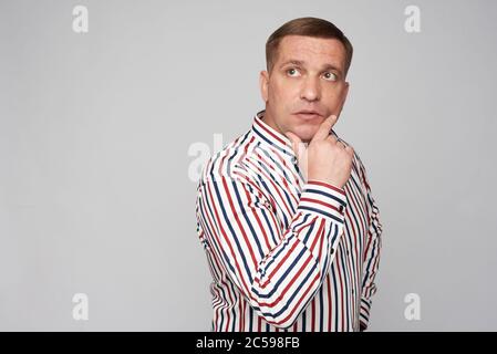 Nachdenklicher Mann mittleren Alters, der aufschaut und nachdenkt. Isoliert auf grauer Studiowand Stockfoto