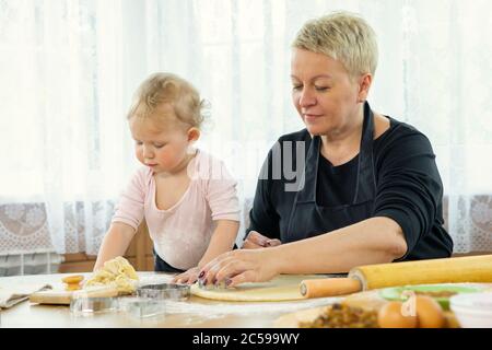 Oma und Enkelin Scheiben Teig mit Cookie Form Backstunde Stockfoto
