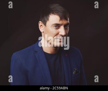 Portrait von bestimmten gut aussehenden Mann trägt blaue Jacke, schwarzer Hintergrund Stockfoto
