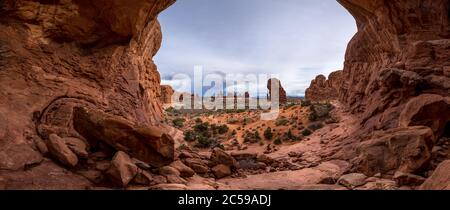 Wunderschöner Aussichtspunkt mit Blick unter der massiven Sandsteinfelsenformation Double Arch an einem bewölkten Tag, Arches National Park, Moab, Utah Stockfoto