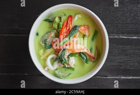 Thai-Essen. Meeresfrüchte grüne Curry-Suppe auf dunklem Holzhintergrund. Draufsicht Stockfoto