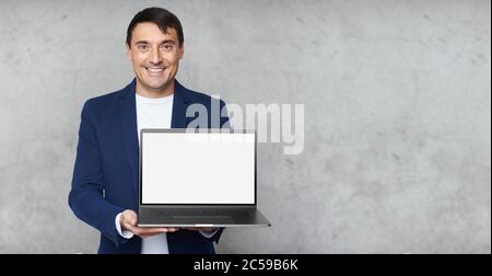 Schöner Mann lächelt und zeigt leeren Bildschirm des Laptop-Computers Stockfoto