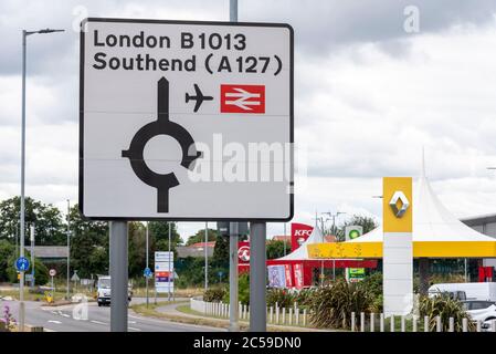 Wegweiser auf der B1013, der Ihnen Wegbeschreibungen nach London und Southend, einschließlich Flughafen und Bahnhof, gibt. Kreisverkehr. Cherry Orchard Way Autoverkäufe Stockfoto