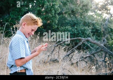 Red Haired Boy Smiles Beim Blick Auf Seine Hand Nach Ein Sturz Stockfoto