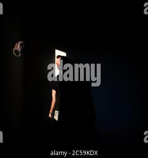 Mann, der in einem dunklen Raum mit Licht steht Stockfoto