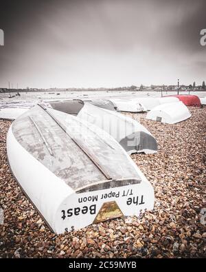 Umgedrehte hölzerne Fischerboote auf einem Kiesstrand am Ufer Stockfoto