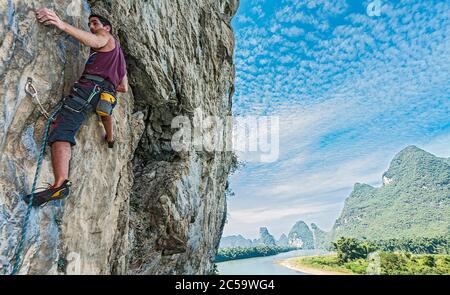 Junger Mann klettert steile Felswand in Yangshuo / China Stockfoto