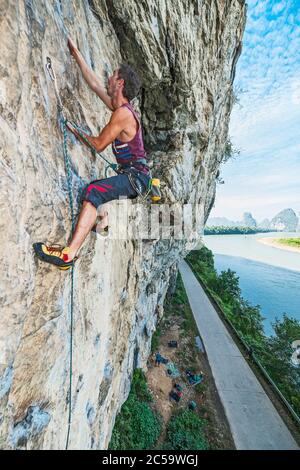 Junger Mann klettert steile Felswand in Yangshuo / China Stockfoto
