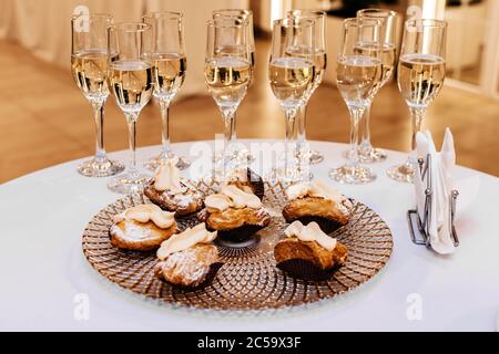 Champagner in Gläsern und ein Teller mit Kuchen auf dem Weißer Tisch Stockfoto