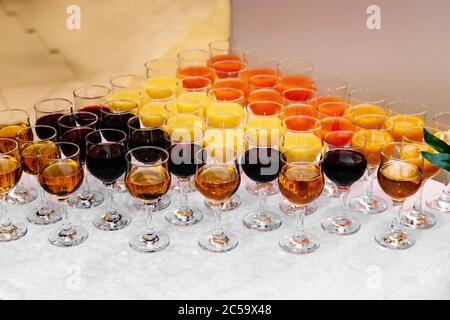 Gläser mit farbigen Getränken auf einem weißen Tisch Stockfoto