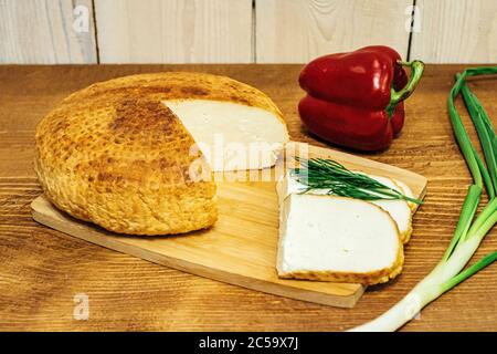 In Scheiben geschnitten â €‹â €‹Käse mit Pfeffer und Kräutern auf einem Holzbrett Stockfoto