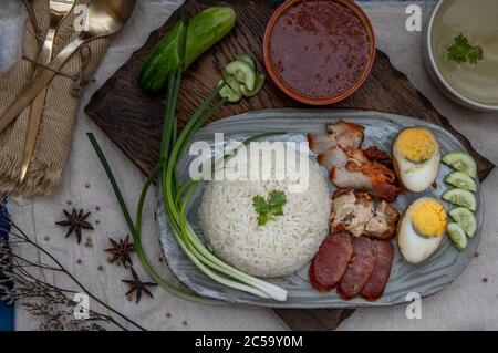 Rotes Schweinefleisch mit Reis (Kao Moo Dang): Rotes Grillpork im thailändischen Stil, Entenei und knuspriger Schweinebauch, geschnittene Gurke mit roter Soße und Brühe. Horizontal Stockfoto