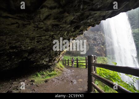 Ein Mädchen, das hinter South Falls im Silver Falls State Park in Oregon, USA, steht. Stockfoto