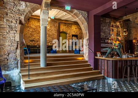 Pudelbar im Hotel Rathof, Kassel, Deutschland. Jeder Bogen sei ein Geschenk, sagt Mitinhaberin Kirstin Kleinkauf. Dieser Bogen, der den Eingangsbereich mit Bistro und Bar verbindet, ist ein besonderer Blickfang, an dem kein Gast unvorsichtig vorbeikommt. Eine kleine Beobachtung an der Seite: Beim Betreten der Bar interessieren sich die Männer mehr für die Statik des alten Steins, während die Frauen ihren Blick über die samtigen Sessel und funkelnden Lampen schweifen lassen Stockfoto