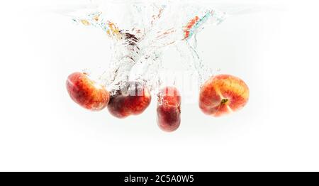 Bündel von Donut Pfirsiche isoliert auf weiß, spritzt in Wasser. Stockfoto