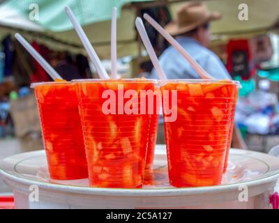 Einige Kunststoff-Einweggläser mit einem Fruchtcocktail gefüllt, auf einem Kunststofftablett. EIN typischer Snack, fotografiert auf dem lokalen Markt der Kolonialschleppe Stockfoto