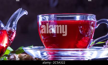 Teestunde: tasse Tee. Kreatives Layout aus einer Tasse Hibiskustee und Teeblätter. Roter Tee, Karkasse, Karkade, Rooibos. Orientalisch, gemütlich, Zeremonie, traditi Stockfoto