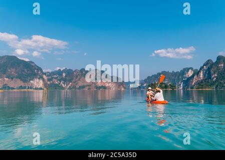 Mutter mit Sohn schwimmt gemeinsam auf dem Kajak am Cheow Lan See im exotischen Thailand. Reisen mit Kindern Konzept Bild. Stockfoto