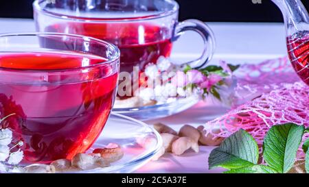 Roter heißer Hibiskus-Tee in einem Glas-Becher. Teestunde: tasse Tee, Karkade, Karkade, Rooibos. Orientalisch, gemütlich, Zeremonie, Tradition, japanisch, belaubt, hygge, autum Stockfoto
