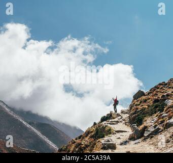 Junge Wandererin Backpacker-Frau, die beim Wandern in Höhenlagen die Bremse zieht Everest Base Camp (EBC) Route mit schneebedeckten Himalaya-Gipfeln im Hintergrund. Stockfoto