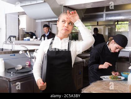 Unglücklich und müde junge Kellnerin warten bestellten Gerichte im Restaurant Küche Stockfoto