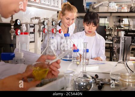 Zwei Studentinnen der Fakultät für Chemie führen Experimente im Universitätslabor durch und zeichnen die Ergebnisse in einem Notizbuch auf Stockfoto