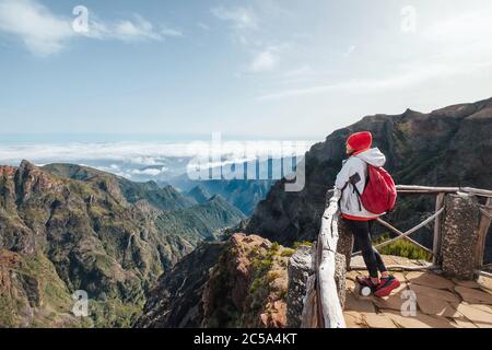 Junge Backpacker-Frau genießt Bergblick beim Trekking auf dem berühmten Bergwanderweg vom Pico do Arieiro zum Pico Ruivo auf dem portugiesischen Madeir Stockfoto