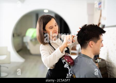 Weibliche Friseur macht Haar Styling für junge Mann, Arbeitstag im Schönheitssalon Stockfoto
