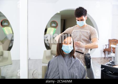 Portrait von männlichen Friseur und weiblichen Kunden in Einweg-Masken und Handschuhe bekommen Haarschnitt in lokalen Haarstudio, neue normale aufgrund Coronavirus outb Stockfoto