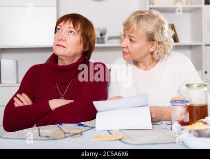 Ältere Frau erklärt Details des Dokuments beleidigt Freundin zu Hause Stockfoto