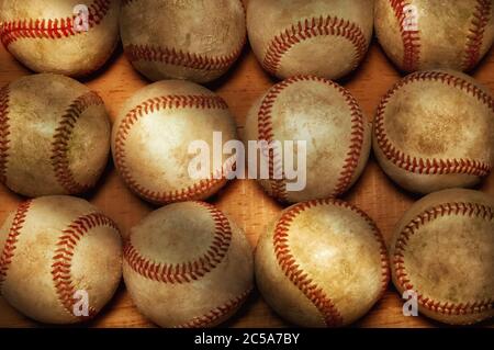 Flach Lay Baseball Stillleben. Ein hoch anwinkeliger Schuss von einem Dutzend gebrauchten Baseballs auf einer Holzoberfläche mit warmem Seitenlicht. Stockfoto