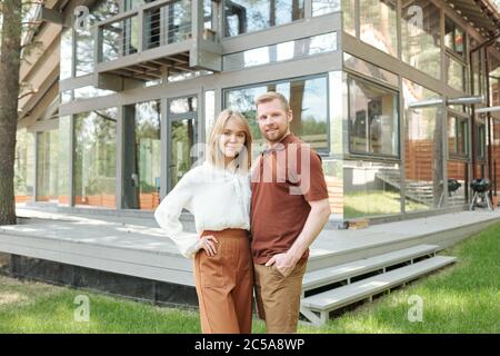 Portrait of content selbstbewusstes junges Paar haben neues Haus gekauft, das sich dagegen posiert Stockfoto