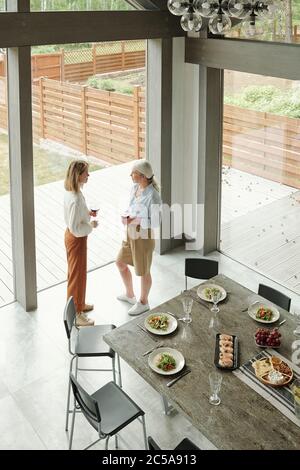 Oben Ansicht der jungen Tochter und ältere Mutter in der modernen Küche des Cottage House und Wein trinken während des Chats stehen Stockfoto