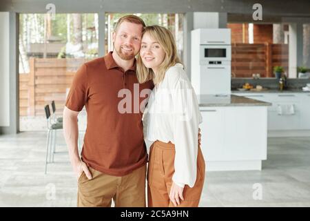 Portrait von glücklichen schönen Paar umarmt gegen moderne Küche in Cottage House Stockfoto