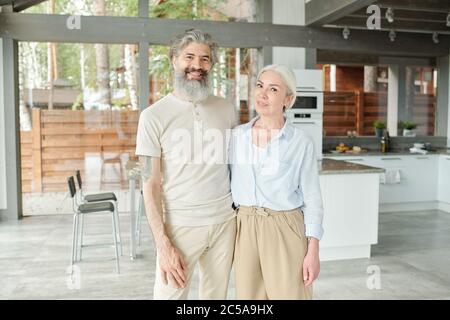 Portrait von lächelnd schöne ältere Paar umarmt gegen Küche in modernen Haus Stockfoto