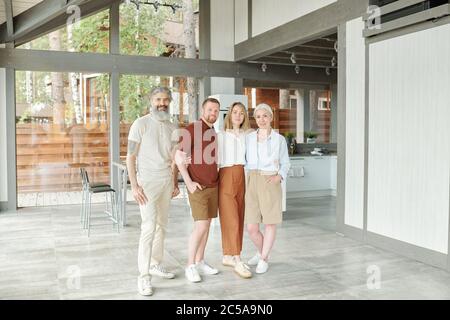 Portrait of content Erwachsene Tochter und Sohn umarmen ältere Eltern in modernen Haus Stockfoto