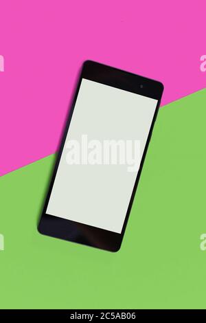 Leeres schwarzes Smartphone mit leerem Bildschirm auf rosa und grünem Hintergrund Stockfoto