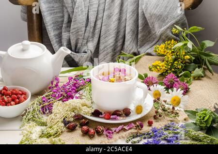 Kräutertee in einer weißen Tasse mit Blumen. Teezeremonie. Tee mit Kamille, mit Wildrose und Klee Stockfoto