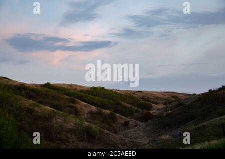 Hügel bedeckt mit Grün, die unter dem wolkigen Himmel glänzen Stockfoto