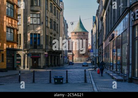 Ein paar Leute in der leeren Straße der Altstadt von Riga mit dem mittelalterlichen Pulverturm Stockfoto