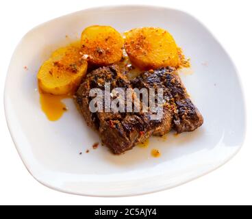 Leckeres gegrilltes Kalbssteak mariniert in pikanten Chimichurri mit Beilage aus ungeschälten gebackenen Kartoffeln al Caliu. Isoliert auf weißem Hintergrund Stockfoto