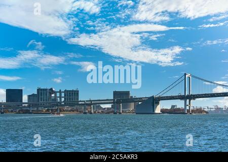 tokio, japan - april 04 2020: Wasserbus fährt auf der Bucht von Tokyo vor der zweischichtigen Regenbogenbrücke mit der Bucht von Odaiba und Einkaufszentren Stockfoto