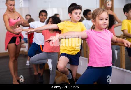 Fokussierte Kinder stehen während des Unterrichts an der Ballettbar im Tanzstudio Stockfoto