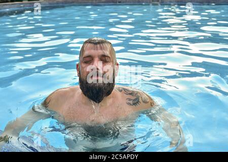 Bärtiger Mann, der in einem Pool schwimmt. Mann mit Bart im Pool. Stockfoto