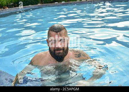 Bärtiger Mann, der in einem Pool schwimmt. Mann mit Bart im Pool. Stockfoto