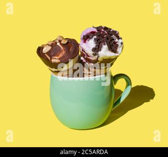 Eis in der Hupe. Eis in einem Horn auf gelbem Hintergrund in einer grünen Tasse. Copyspace Stockfoto