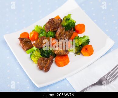 Gebratenes Huhn Herzen mit gekochten Brokkoli und gebackene Karotten auf weiße Platte serviert. Stockfoto