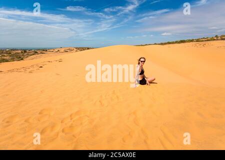 Schöne kaukasische Mädchen mit Spaß auf roten Sanddünen in Mui Ne, Phan Tiet Bereich in Vietnam. Landschaft mit blauem Himmel an sonnigen Tagen. Stockfoto