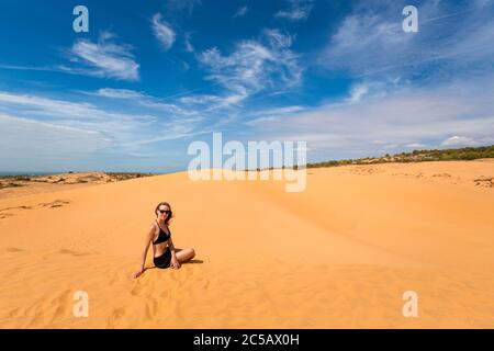 Schöne kaukasische Mädchen mit Spaß auf roten Sanddünen in Mui Ne, Phan Tiet Bereich in Vietnam. Landschaft mit blauem Himmel an sonnigen Tagen. Stockfoto